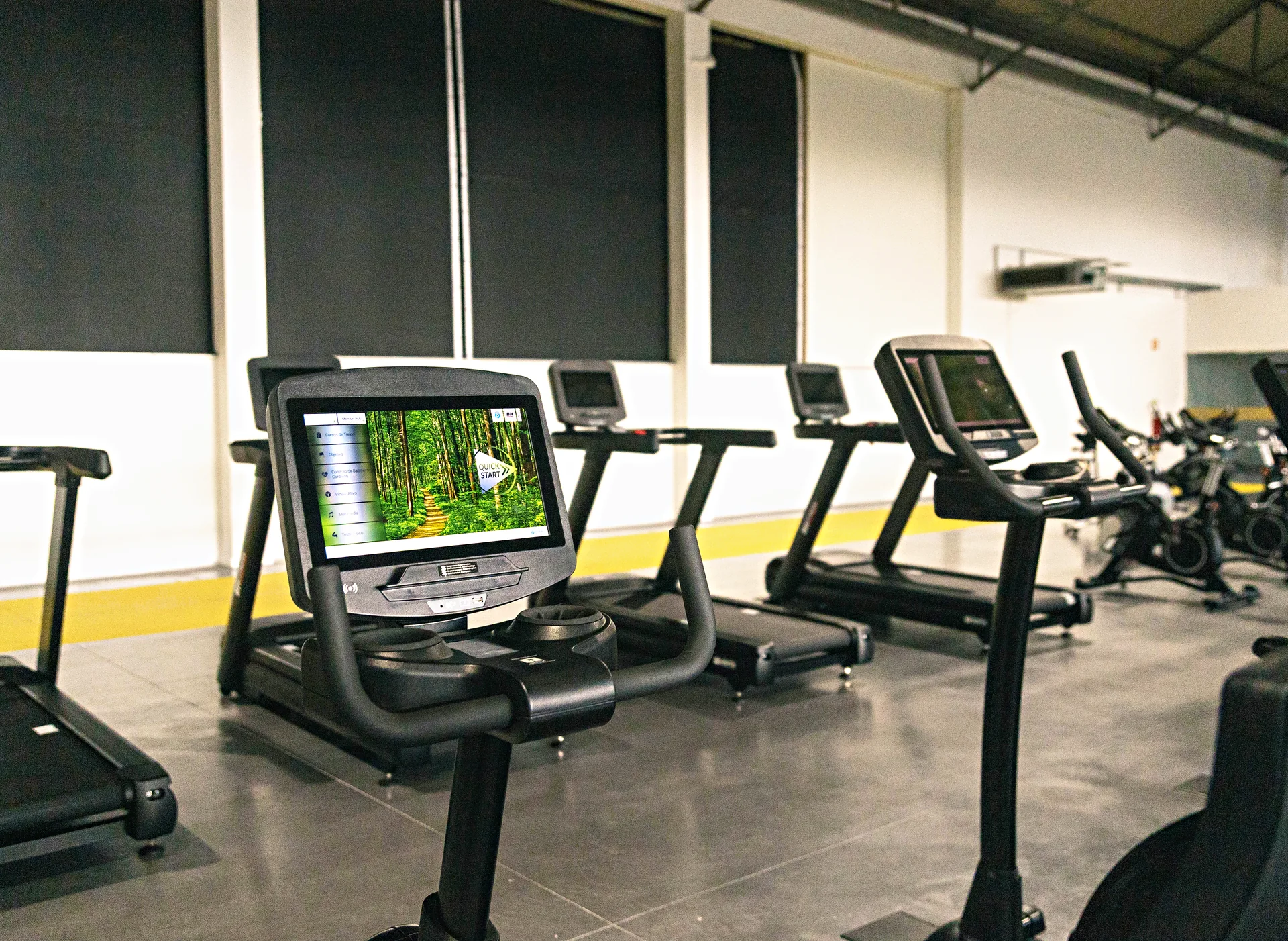Passadeiras e bicicletas na sala de cardio do Arena Club