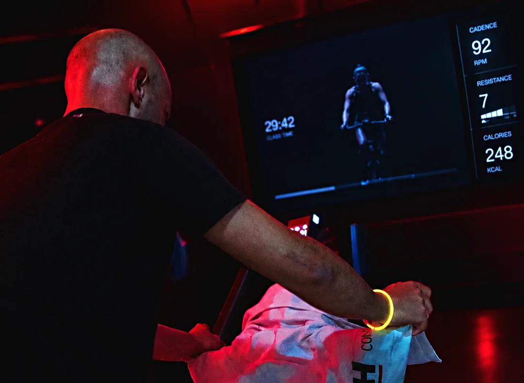 Sócio numa aula virtual de ciclismo com luz vermelha no Arena Fitness